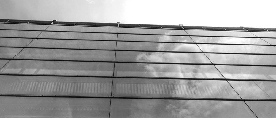 Glasfassade eines modernen Gebäudes mit Wolkenspiegelung in Schwarzweiß