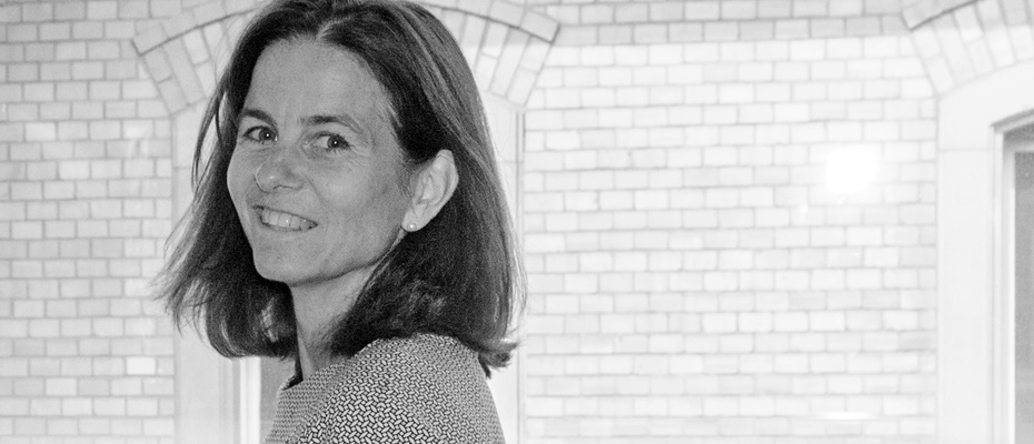 Melanie Scheibel lächelnd vor einem historischen Backsteinbogen in Schwarzweiß